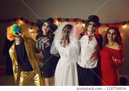 Portrait of multiracial adult friends in spooky costumes for Halloween at home party. 128758634