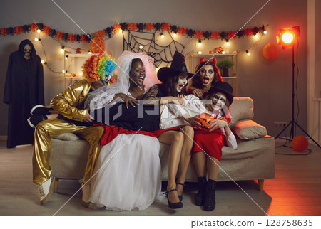Group of friends in spooky costumes laughing and having fun at a Halloween party 128758635