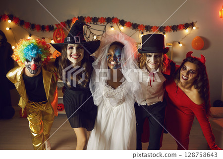 Portrait of group of young cheerful and crazy friends having fun at Halloween party. 128758643