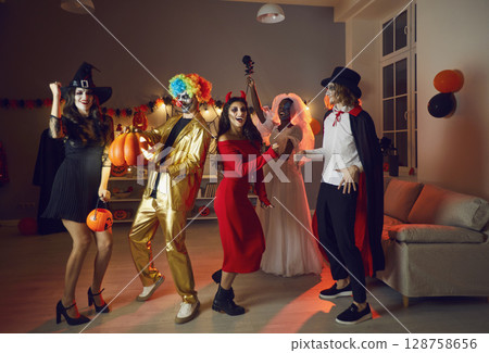 Overjoyed friends dance at Halloween party 128758656