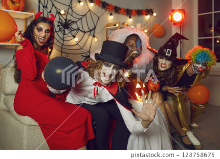 Happy adult friends in spooky costumes having fun at Halloween party all together Happy adult friends in spooky costumes having fun at Halloween party all together 128758675