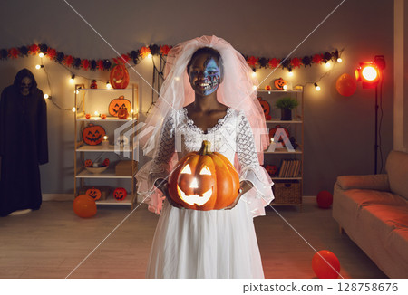 Portrait of young smiling dark skinned woman dressed as dead bride at Halloween party. 128758676