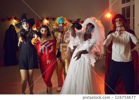 Group of adult people in spooky costumes walking like zombies at Halloween party Group of adult people in spooky costumes walking like zombies at Halloween party 128758677