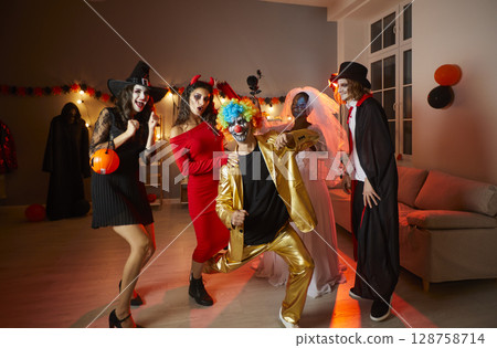 Group of happy young friends in costumes having fun at a Halloween party at home 128758714