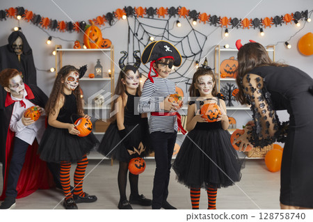 Children in spooky costumes trick or treating and getting candy at Halloween party Children in spooky costumes trick or treating and getting candy at Halloween party 128758740