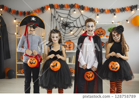 Group of children in different spooky Halloween costumes holding pumpkin baskets 128758789