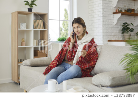Woman who is being treated at home with high temperature calls her doctor for advice on medication. Woman who is being treated at home with high temperature calls her doctor for advice on medication. 128758897