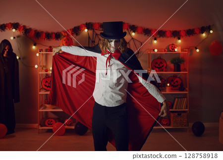 Adult man dressed up in a red and black vampire cloak for a spooky Halloween party 128758918