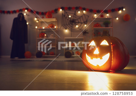 Festive Halloween background with smiley jack-o-lantern on floor in dark decorated room 128758953