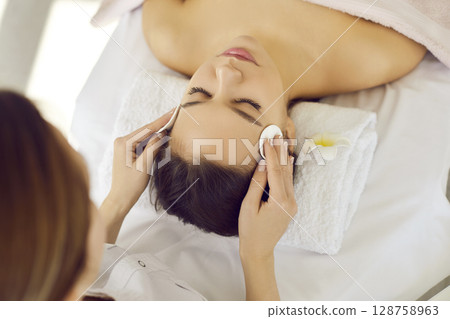 Beautician male facial procedures to woman client 128758963