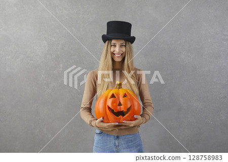 Happy woman with pumpkin in her hands on which is carved funny face in style of Halloween. Happy woman with pumpkin in her hands on which is carved funny face in style of Halloween. 128758983