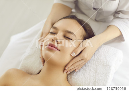 Woman getting face massage and cosmetic facial treatment for clean young healthy skin 128759036
