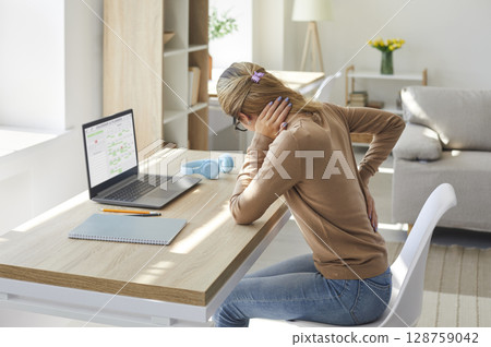 Woman who works in sitting posture on her laptop computer is suffering from back pain Woman who works in sitting posture on her laptop computer is suffering from back pain 128759042