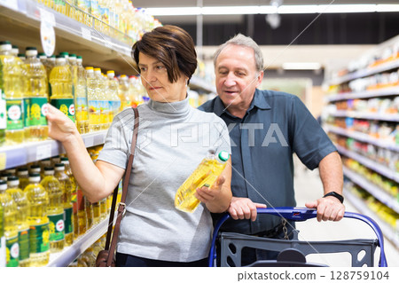Elderly married couple choosing sunflower oil together in the grocery department of supermarket 128759104