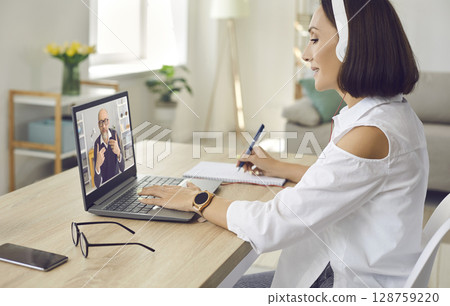 Senior business woman sitting at home watching business training or online webinar on laptop. 128759220