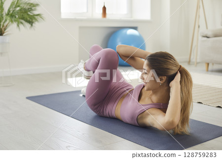 Happy sporty young woman doing bicycle crunches during her fitness workout at home Happy sporty young woman doing bicycle crunches during her fitness workout at home 128759283