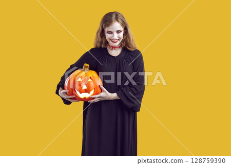 Halloween portrait of mad, spooky and evil woman with glowing jack-o-lantern in hands. Halloween portrait of mad, spooky and evil woman with glowing jack-o-lantern in hands. 128759390