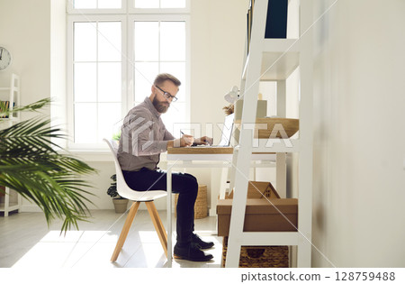 Serious focused businessman working on important work project in his bright home office. Serious focused businessman working on important work project in his bright home office. 128759488
