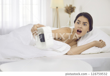 Young woman who has an alarm clock oversleeps in the morning and is late for work 128759532
