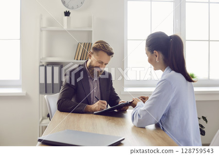 Happy man signs employment contract after successful interview for new position. 128759543