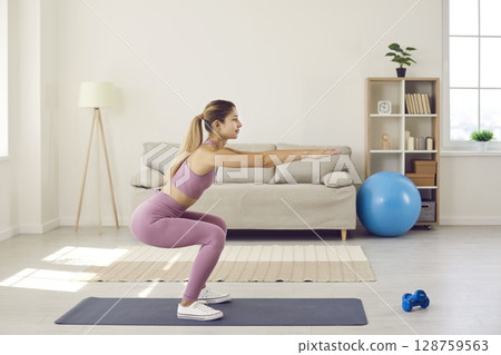 Toned woman in sportswear training at home 128759563