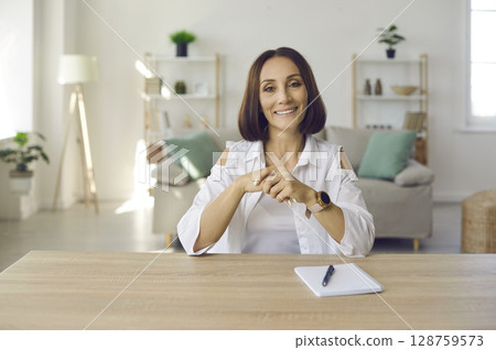 Stylish senior woman talking and conducting online client counseling while sitting in home office. 128759573