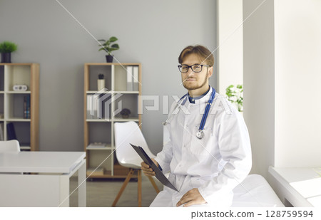 Portrait of male doctor in white coat in hospital 128759594