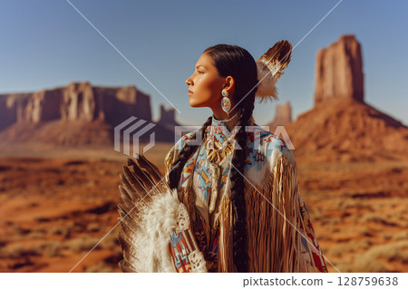 A woman wearing a colorful outfit stands in front of a mountain range 128759638