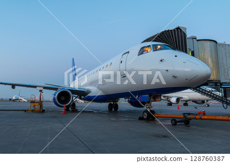 Modern passenger airliner at the skybridge on the airport early in the morning Modern passenger airliner at the skybridge on the airport early in the morning 128760387