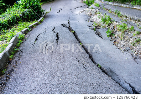 Cracked asphalt road damaged by landslide, showcasing deep fissures and vegetation encroaching, illustrating the impact of natural disasters on infrastructure and environment Cracked asphalt road damaged by landslide, showcasing deep fissures and vegetation encroaching, illustrating the impact of natural disasters on infrastructure and environment 128760428