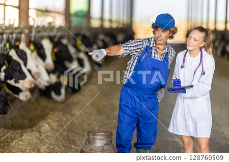 Young female vet discussing something on tablet with male farmer Young female vet discussing something on tablet with male farmer 128760509