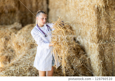 Young woman veterinarian checking straw for cows Young woman veterinarian checking straw for cows 128760510