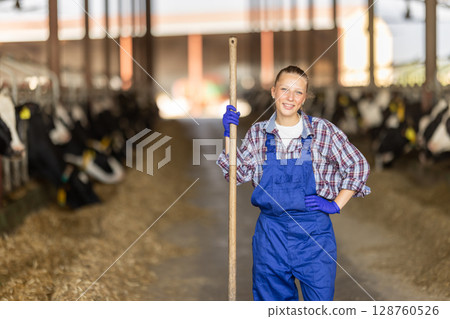 Young female farmer standing with pitchfork Young female farmer standing with pitchfork 128760526