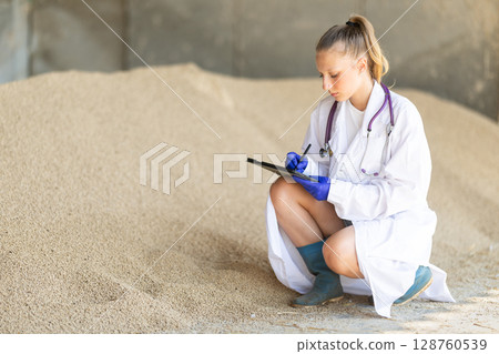 Girl vet with tablet inspect granulated feed in storage Girl vet with tablet inspect granulated feed in storage 128760539