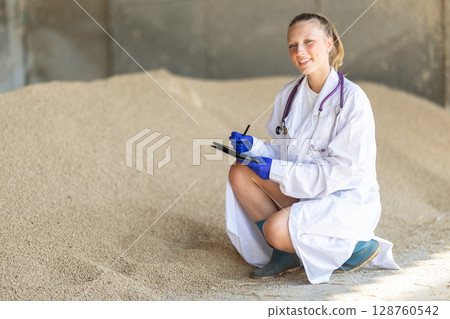 Girl vet with tablet inspect granulated feed in storage Girl vet with tablet inspect granulated feed in storage 128760542