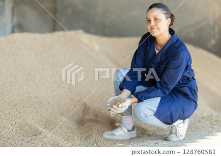 Asian woman farmer inspect granulated feed in storage Asian woman farmer inspect granulated feed in storage 128760581