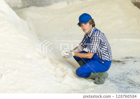 Man worker inspect powdered feed in storage 128760584