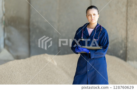 Asian woman farmer with tablet inspect granulated feed in storage Asian woman farmer with tablet inspect granulated feed in storage 128760629