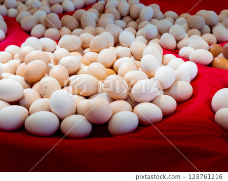 Abundance of eggs on vibrant red fabric background 128761216