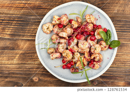 Fried shrimps with berry marinade on wooden surface. 128761534