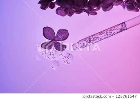 Cosmetic pipette with serum and lilac flowers on a purple background. Cosmetic pipette with serum and lilac flowers on a purple background. 128761547
