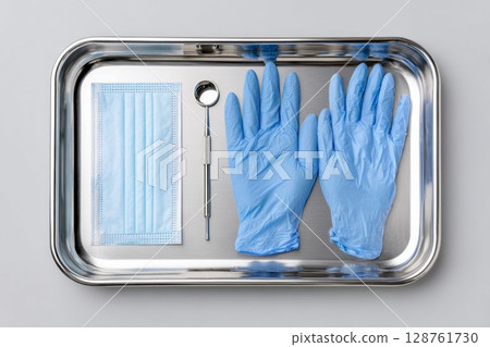 Medical equipment tray with blue gloves, mask, dental mirror, and sterile tools for healthcare 128761730
