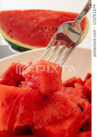 Fresh watermelon slices on a plate with a fork ready to enjoy juicy summer fruit Fresh watermelon slices on a plate with a fork ready to enjoy juicy summer fruit 128761874