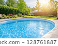 Sparkling swimming pool surrounded by lush greenery and vibrant flowers in a sunny backyard 128761887