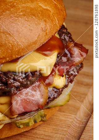 Delicious burger with melted cheese and crispy bacon on wooden board 128761898