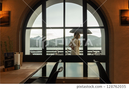 view from the cafe of a man and a woman under an umbrella against the background of mountains view from the cafe of a man and a woman under an umbrella against the background of mountains 128762035