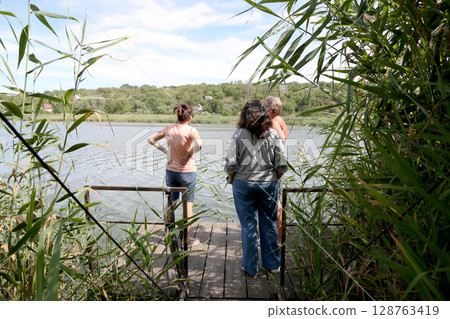 Women on the pier by the river Women on the pier by the river 128763419