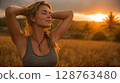 Woman Relaxing in a Golden Wheat Field at Sunset 128763480