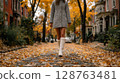 Woman in Animal Print Coat and White Boots Walking on an Autumn Street 128763481