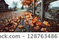 Wet Autumn Leaves on Rustic Wooden Bench 128763486